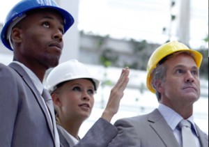 three people with hard hats on staring at something on a construction site